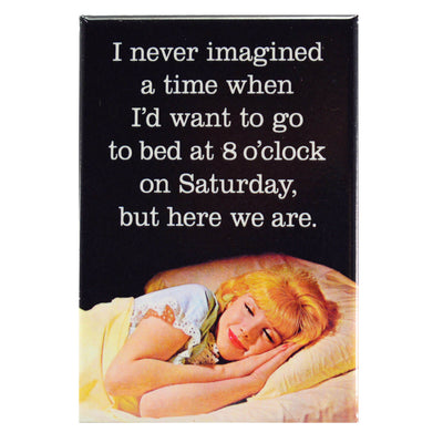 Retro lady laying in bed with her head on the pillow and text saying " I never imagined a time when I'd want to go to bed at 8 o'clock on saturday, but here we are" on a rectangular fridge magnet