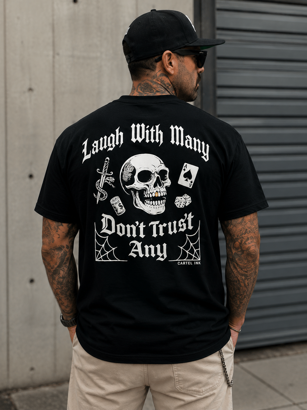 Tattooed man wearing a black shirt with laugh with many don't trust any writing on the back
