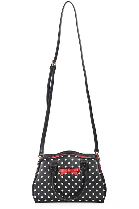 front view of black handbag with white polka dots and red inside and long strap