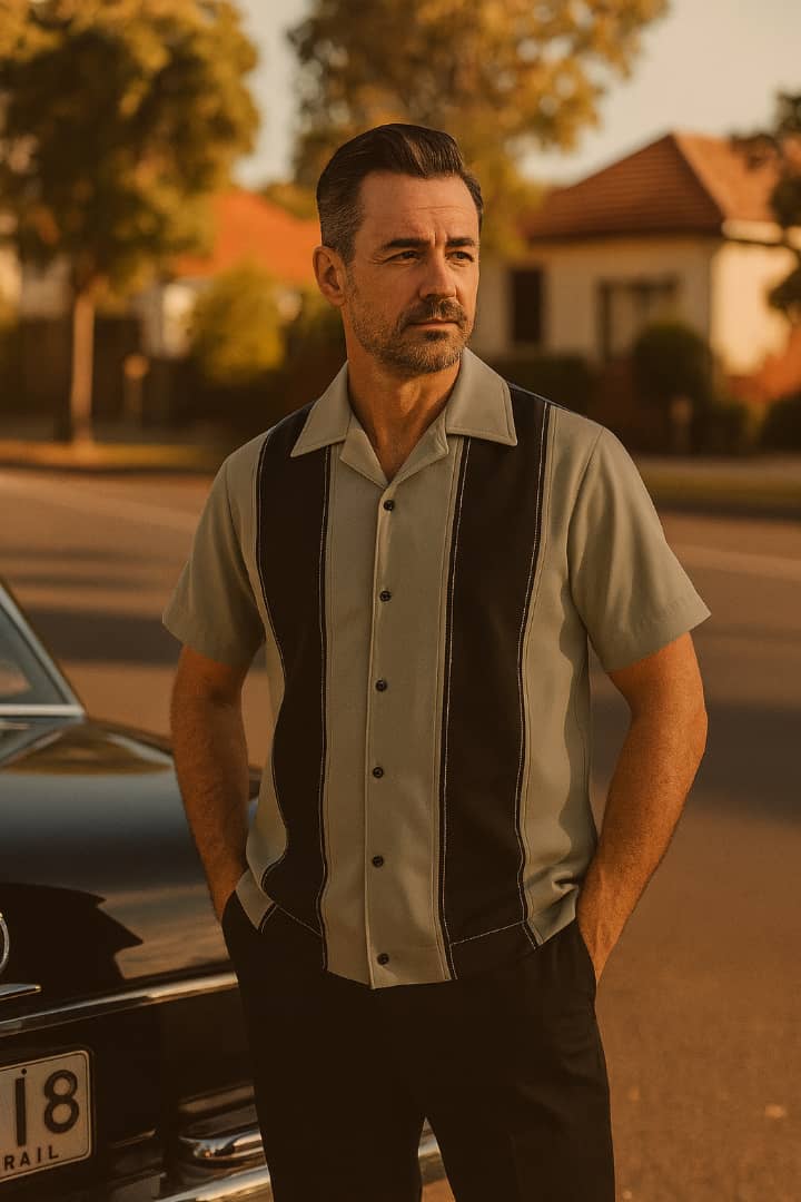 Man in a vintage shirt standing next to a car with a warm, sunset-like filter.