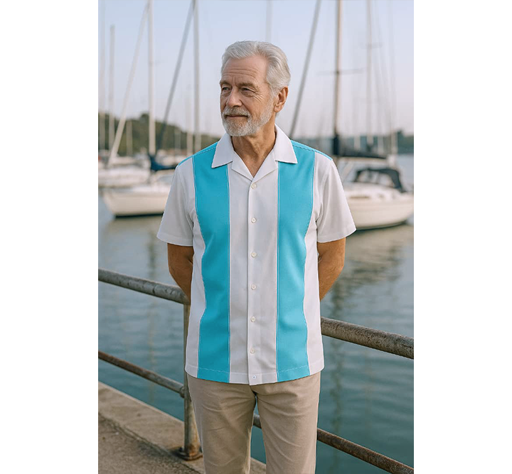 Man wearing a aqua and white striped shirt by a marina with sailboats.
