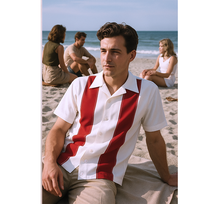 Man wearing a red and white striped shirt sitting on a beach with people in the background.