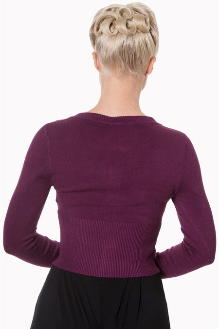 Back image of lady wearing a aubergine cardigan and black skirt