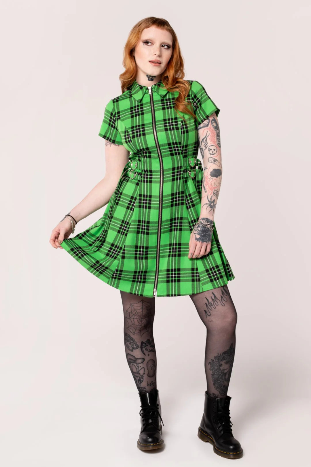 Person wearing a green plaid dress with black accents on a white background