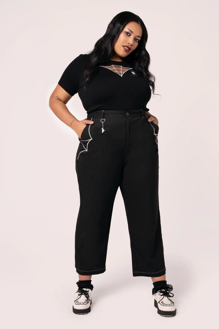 Woman wearing a black outfit with white accents on a plain background