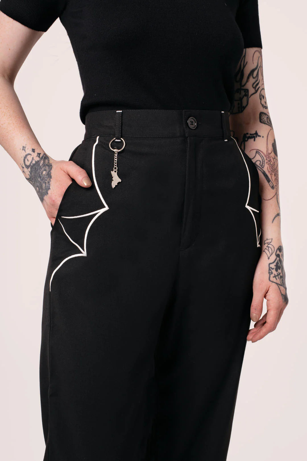 Person wearing black pants with white spider designs on a light pink background