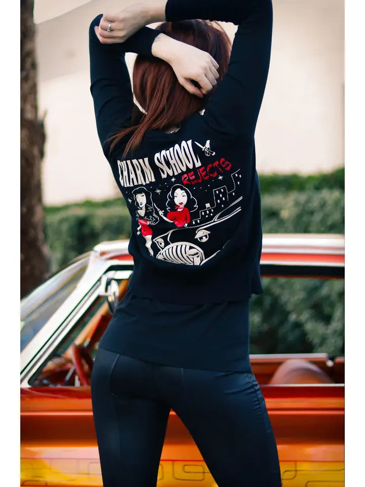 Person wearing a black sweatshirt with graphic design in front of a vintage car.