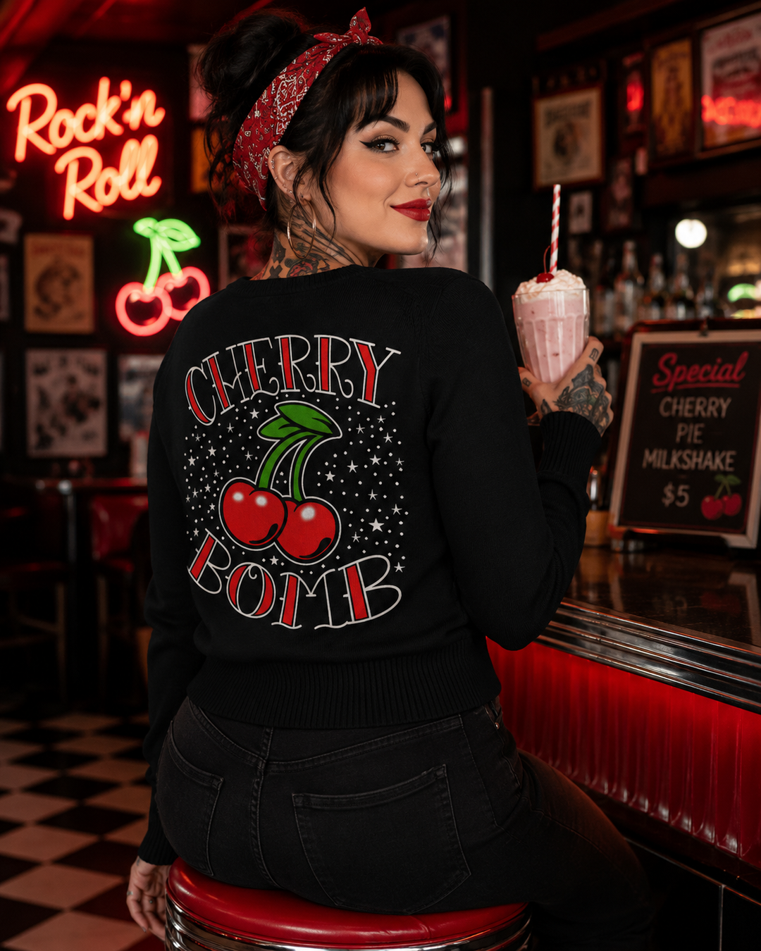 Woman in a bar wearing a black sweater with 'Cherry Bomb' design, holding a milkshake.