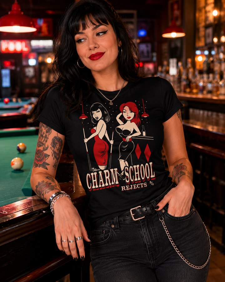 Woman wearing a black t-shirt with graphic design of charm school rejects in a bar setting