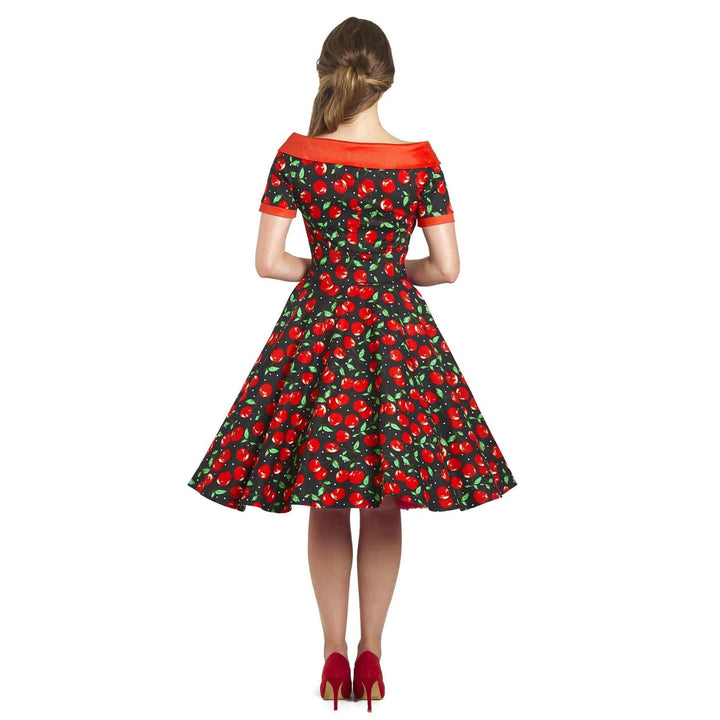 Back image of young lady wearing a boat neck black dress with cherry pattern 