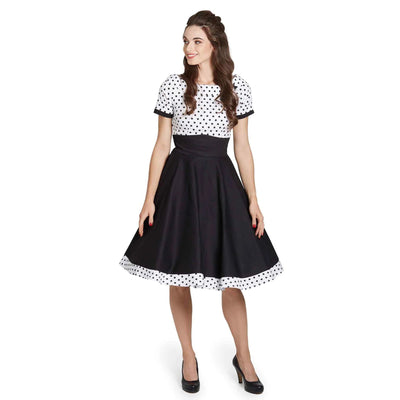 Front image of a lady wearing a black and white dress with black polka dots