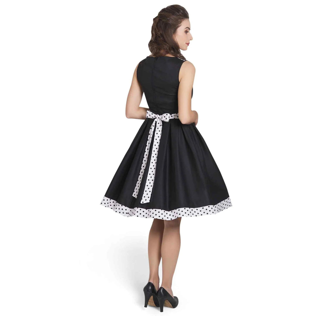 Back image of a lady wearing a black dress with white with black polka dot hem and neckline
