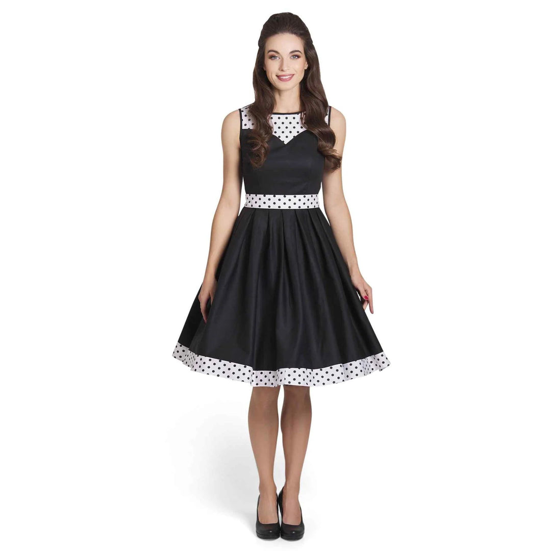 Front image of a lady wearing a black dress with white with black polka dot hem and neckline