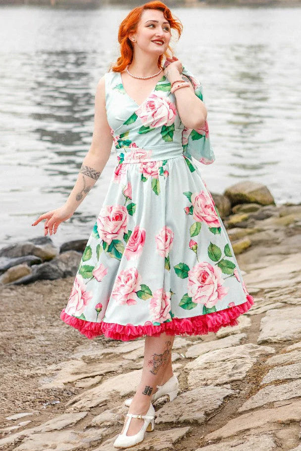 Woman in a floral dress standing by a body of water.