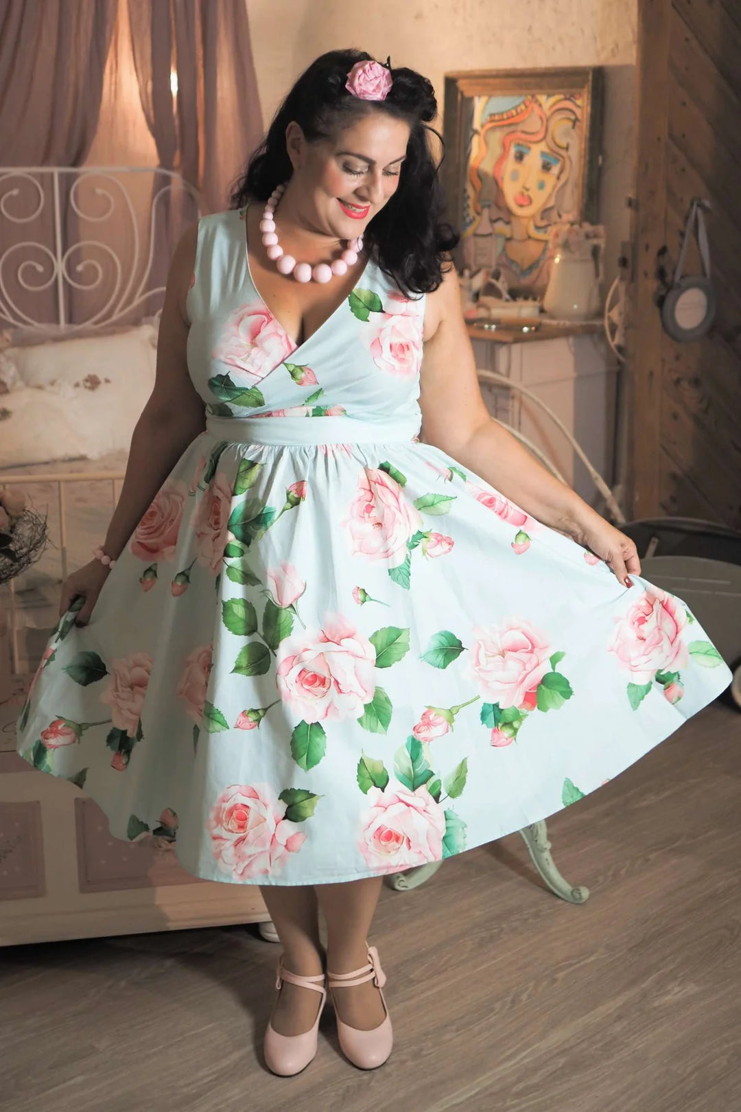 Woman wearing a floral dress in a room with wooden floor and decorative elements.