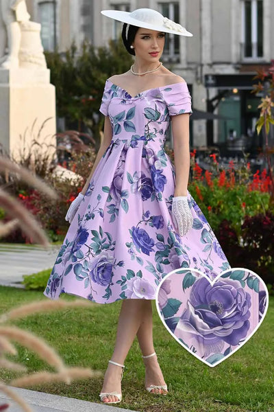Woman in a floral dress standing outdoors with a close-up of a purple rose.