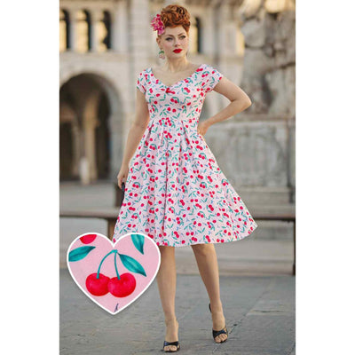 Image of a lady walking posing wearing an off the shoulder pink dress with red cherry design