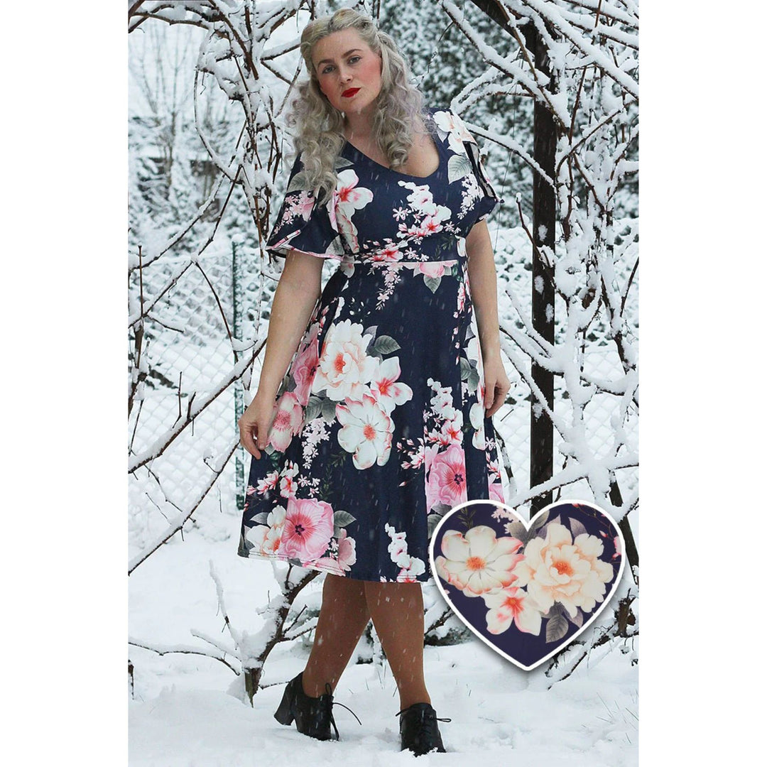 Image of a lady posing in the snow wearing a navy blue dress with pink and light yellow floral pattern