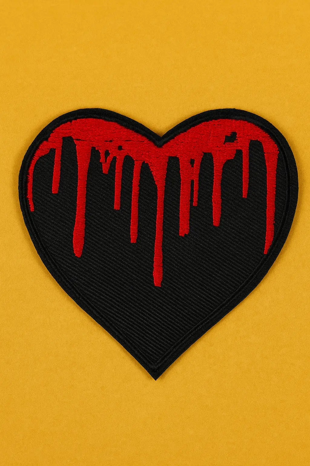 Black heart patch with red dripping blood on a yellow background.