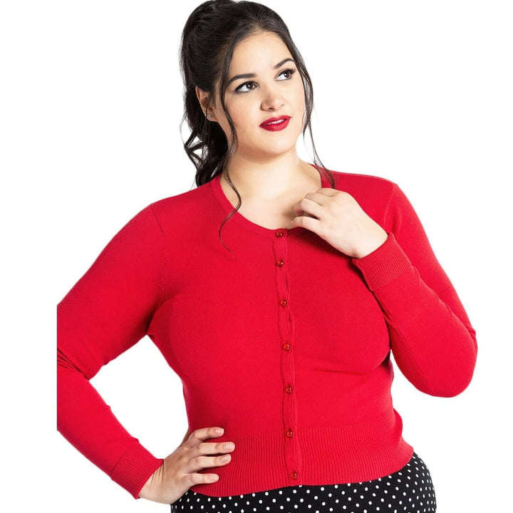 Woman wearing a bright red cropped cardigan over a polka-dot garment on a white background.