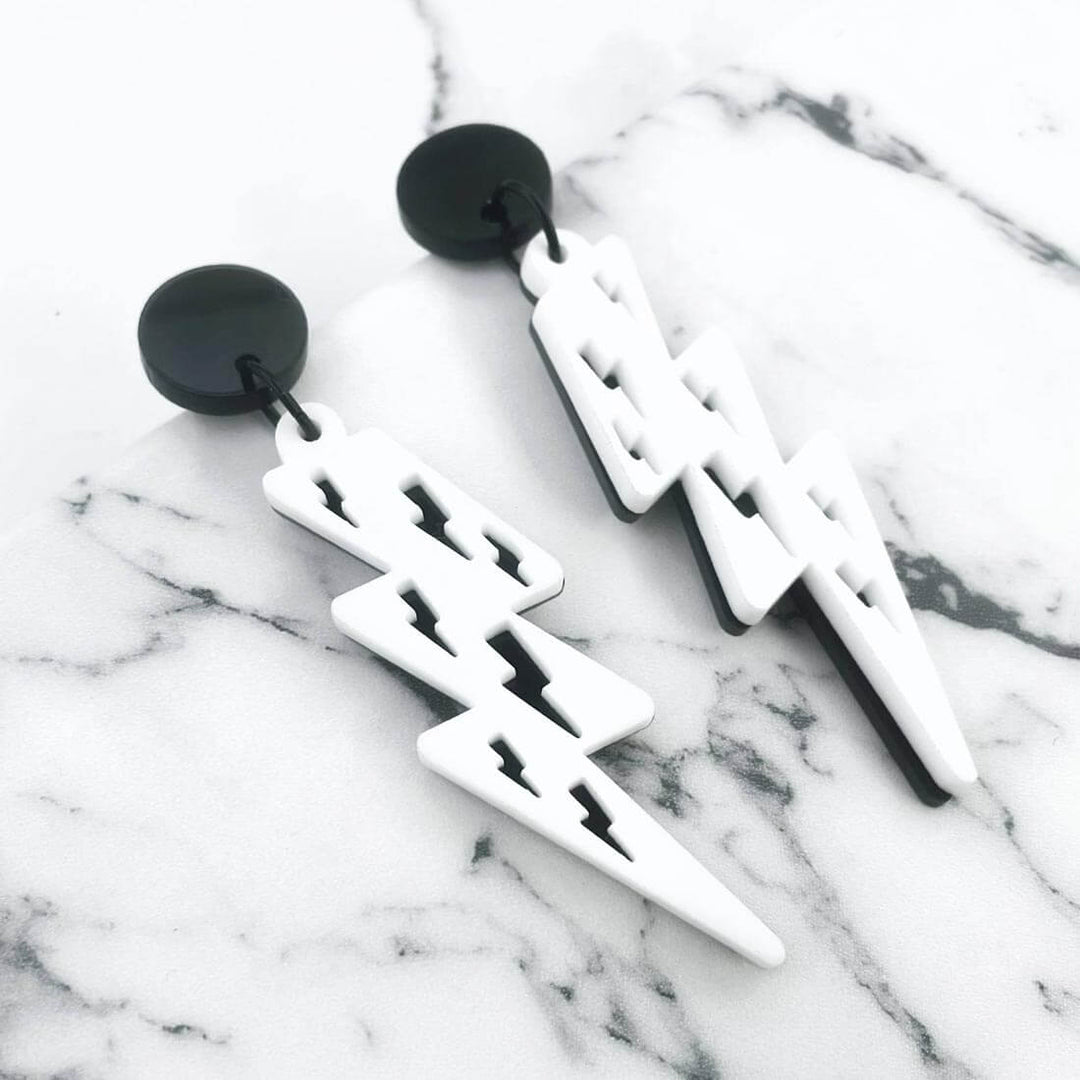 Lost Minds Earrings - Layered Lightning Bolts - Black/White Studs against marble background