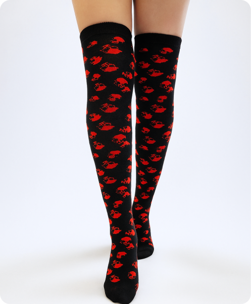 Black over-the-knee socks featuring a repeated red skull pattern on a white background.