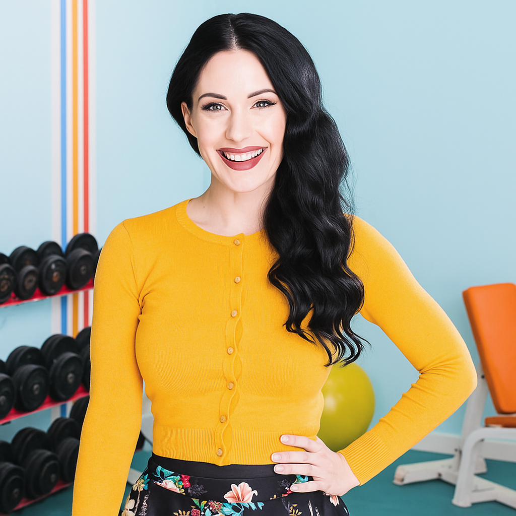 Woman in a yellow sweater posing in a gym setting
