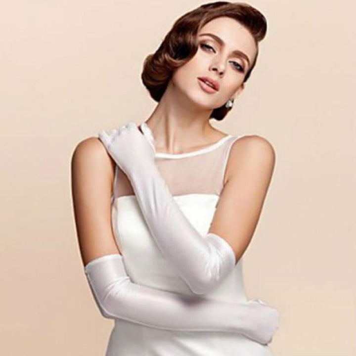 A woman wearing long white satin gloves with a sleeveless white dress.