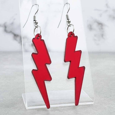 Cool Alternative 80s hook earrings in the shape of lighning bolts. They are red mirror laser cut acrylic on a plastic shop display
