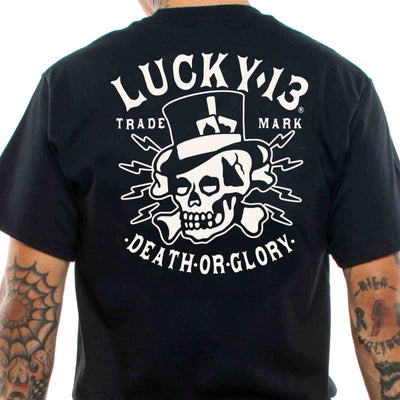 Black Lucky 13 t-shirt, worn by a man with tattooed arms. The motif is a skulland crossbones wearing a tophat