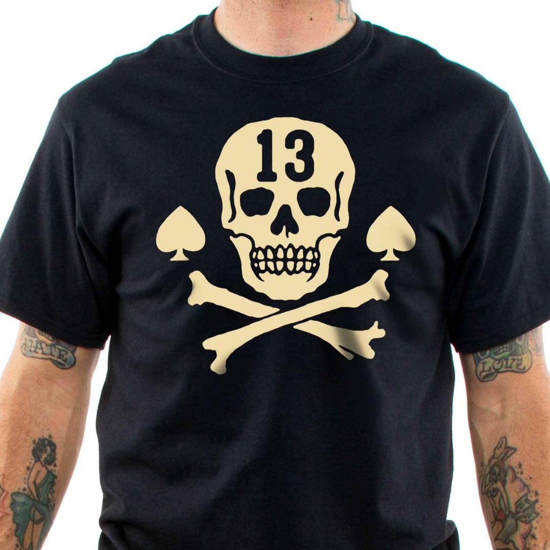 Front view of tattooed model wearing the Lucky 13 Pirate Skull t-shirt. Cream Skull and crossbones with aces at the side and a "13' cuto of of the forehead of the skull